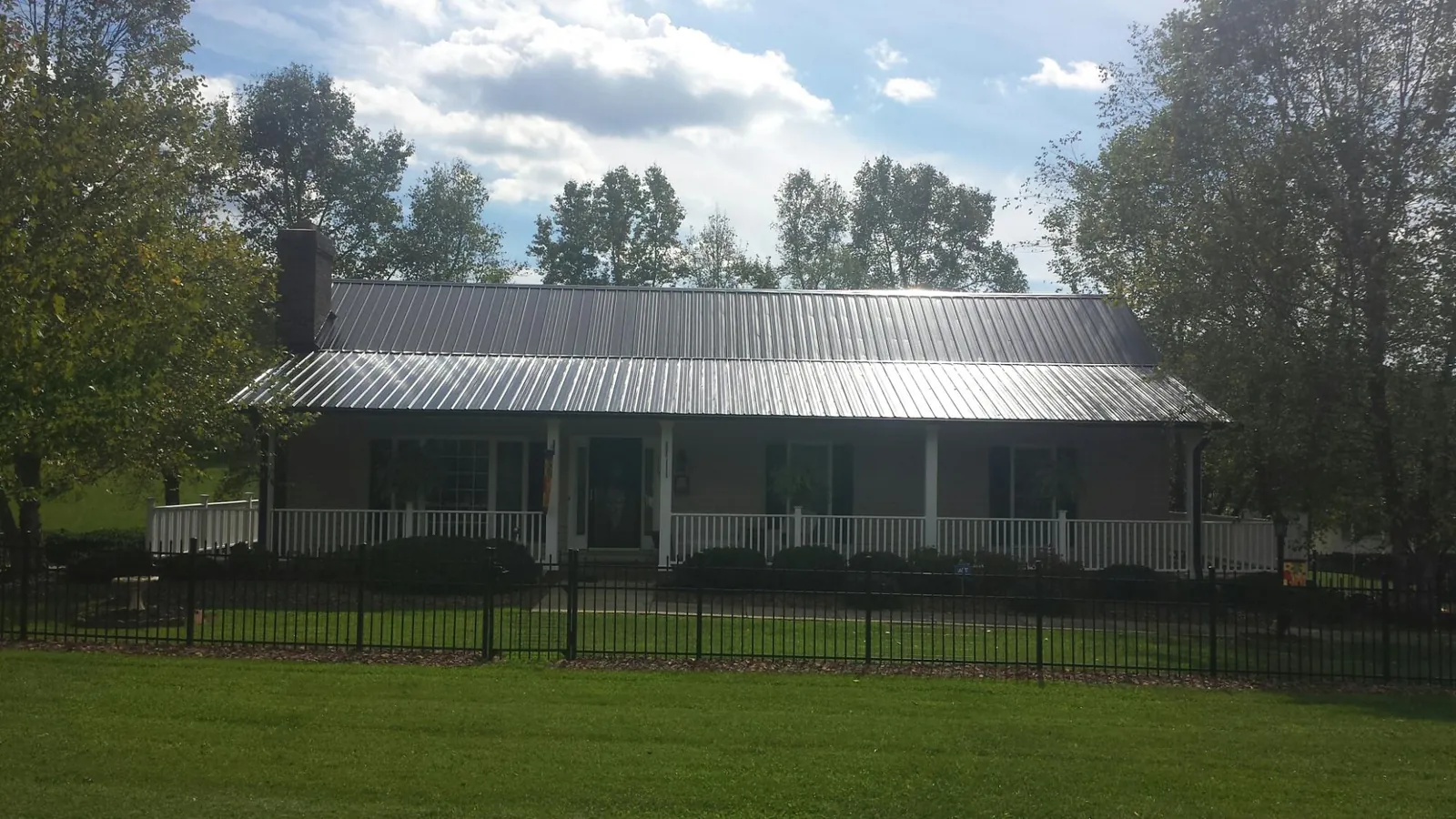 Gray metal roof on a brick ranch with a full width front porch — Gutter Guard Installation work by our crew in Ulysses
