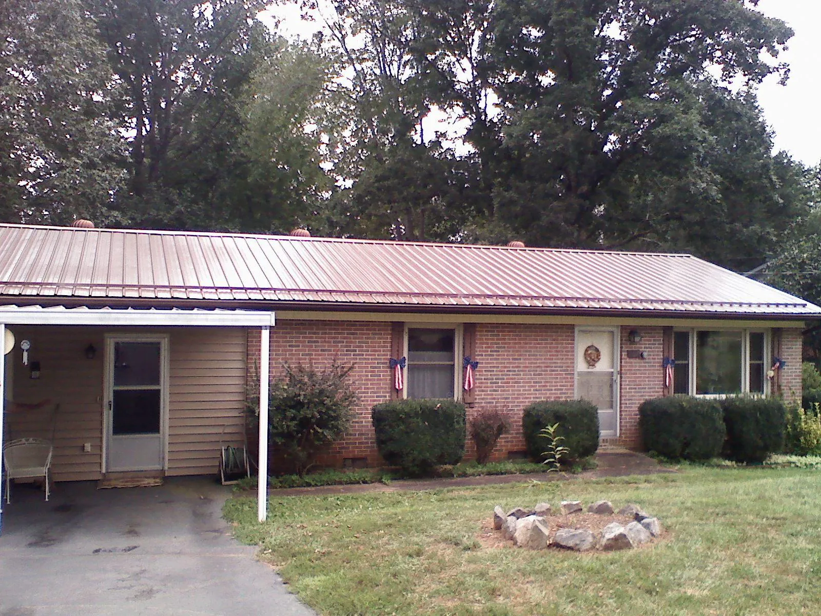 Bronze metal roof and carport on a brick ranch home — Roof Repair work by our crew in Ulysses